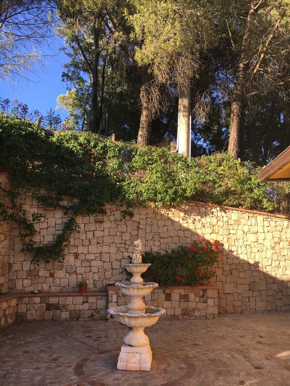 A stone wall with a tiered fountain and a statue in the center.