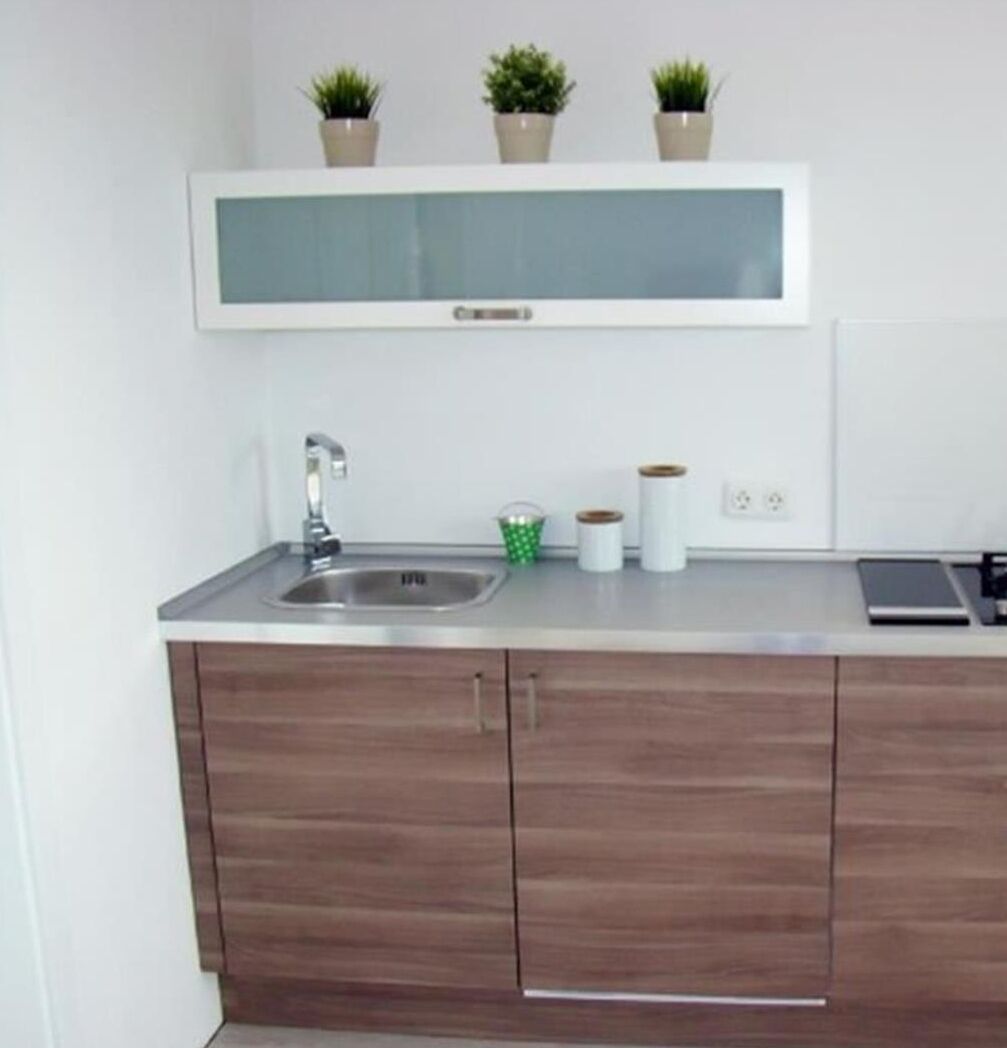 Een koelkast, een vaatwasser, kookgerei, borden en bestek