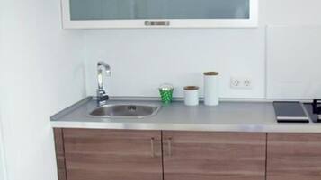 Een koelkast, een vaatwasser, kookgerei, borden en bestek