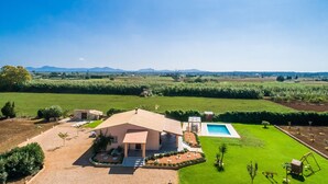Une maison avec une piscine, entourée d’une pelouse et d’un jardin bien entretenus.