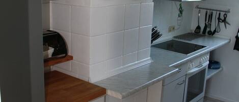 A kitchen with white cabinets, a stainless steel refrigerator, a wooden countertop, and a tiled backsplash.