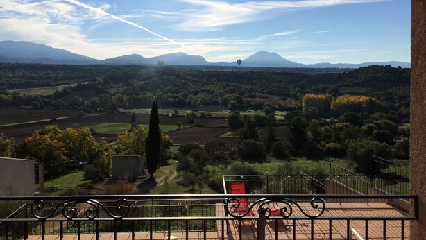 A balcony with a view of a mountainous landscape, including a hot air balloon in the distance. - Detached vacation home in a quiet location (Puimoisson)