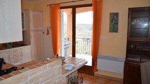 A kitchen with a tiled backsplash, a sink, cabinets, and a window with curtains. - Detached vacation home in a quiet location (Puimoisson)