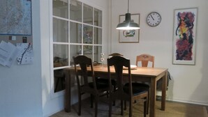 A dining area with a wooden table and chairs, a hanging pendant light, a wall clock, and a framed painting. - City Apartment in Frederiksberg with 2 bedrooms sleeps 4 (Frederiksberg)
