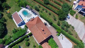 Vista aérea de una propiedad residencial con piscina, patio cubierto y jardín bien cuidado.