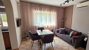 Una sala de estar moderna con una mesa de comedor, sofá y una planta en maceta.