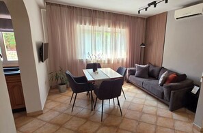 Ein modernes Wohnzimmer mit Esstisch, Sofa und einer Zimmerpflanze.