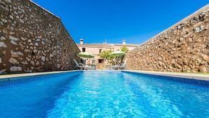 A swimming pool with stone walls and a view of a building in the background.