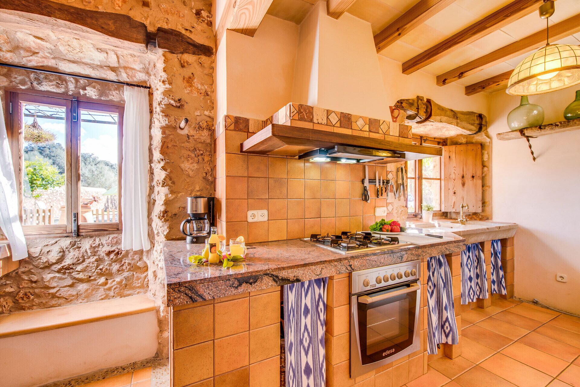 Une cuisine rustique avec des murs en pierre apparentes, une cuisinière à gaz et un four encastré.