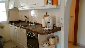 A compact kitchen with a stove, sink, and coffee maker. - Modern apartment: electricity, washing machine WIFI, bed linen, towels INCL. 4 p (Calpe)