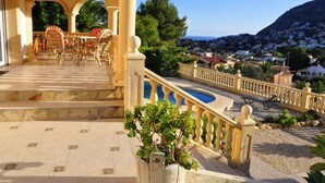A hotel with a terrace, outdoor seating, and a view of a mountainous landscape. - Modern apartment: electricity, washing machine WIFI, bed linen, towels INCL. 4 p (Calpe)