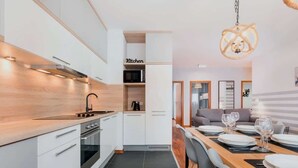 Eine moderne Küche mit weißen Schränken, einem eingebauten Herd und einem Essbereich mit einem Holztisch, gedeckt für vier Personen.
