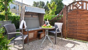 An outdoor seating area with a covered table, two chairs, and a decorative umbrella. - Cozy vacation apartment in Heringsdorf with terrace - 400 m to the beach (Seebad Heringsdorf)