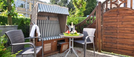 An outdoor seating area with a covered table, two chairs, and a decorative umbrella.