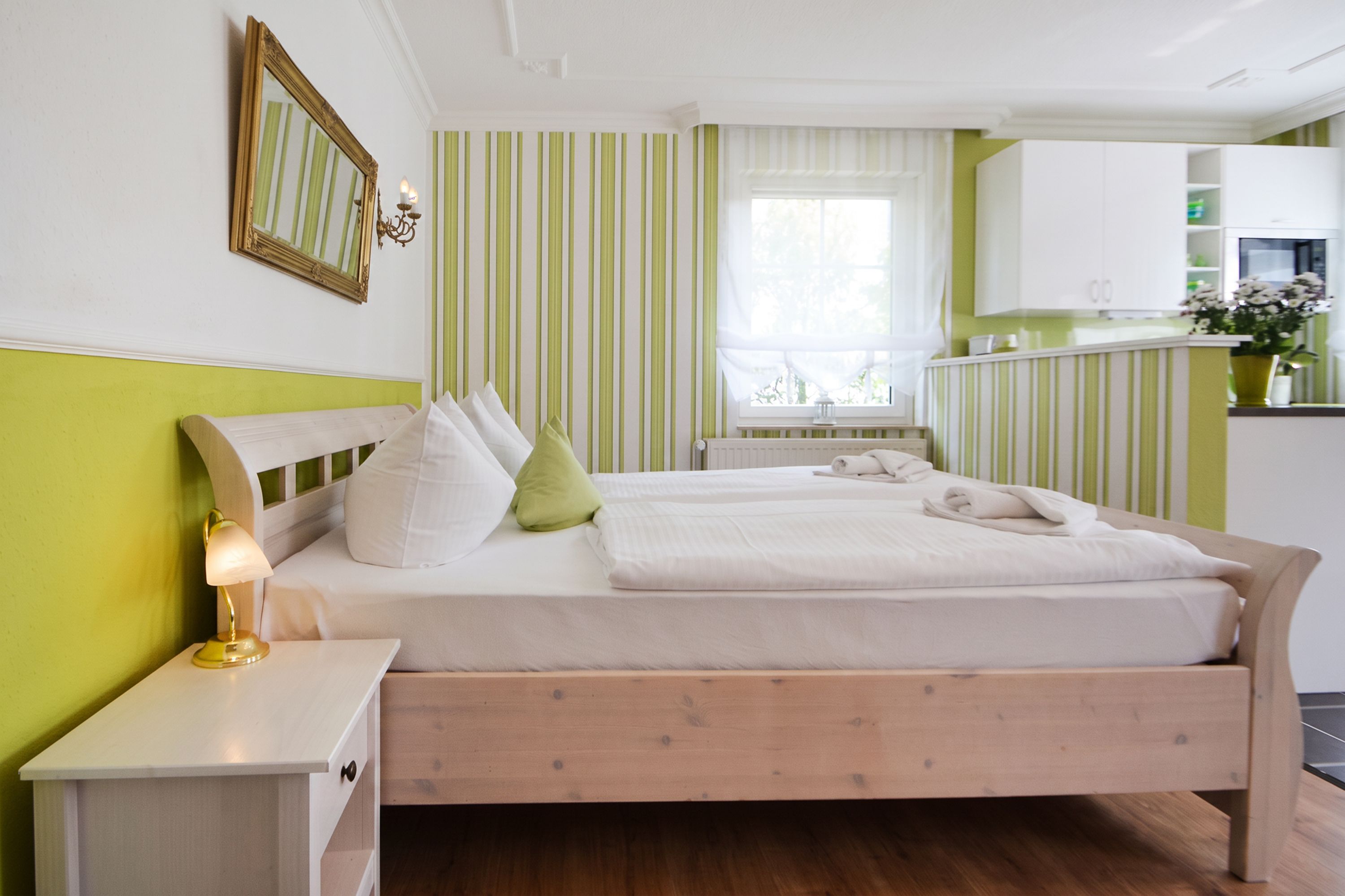 Ein ordentlich eingerichtetes Schlafzimmer mit Bett, Nachttisch und einem Fenster mit Vorhängen.