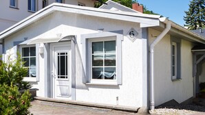 A single-story building with a white facade, a front door, and two windows.