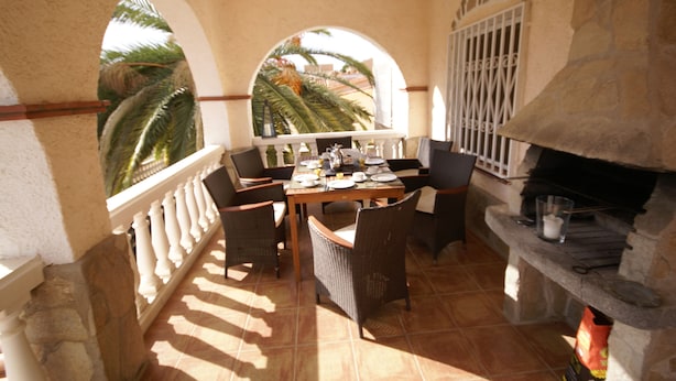 A patio with a stone fireplace, dining table, and chairs.