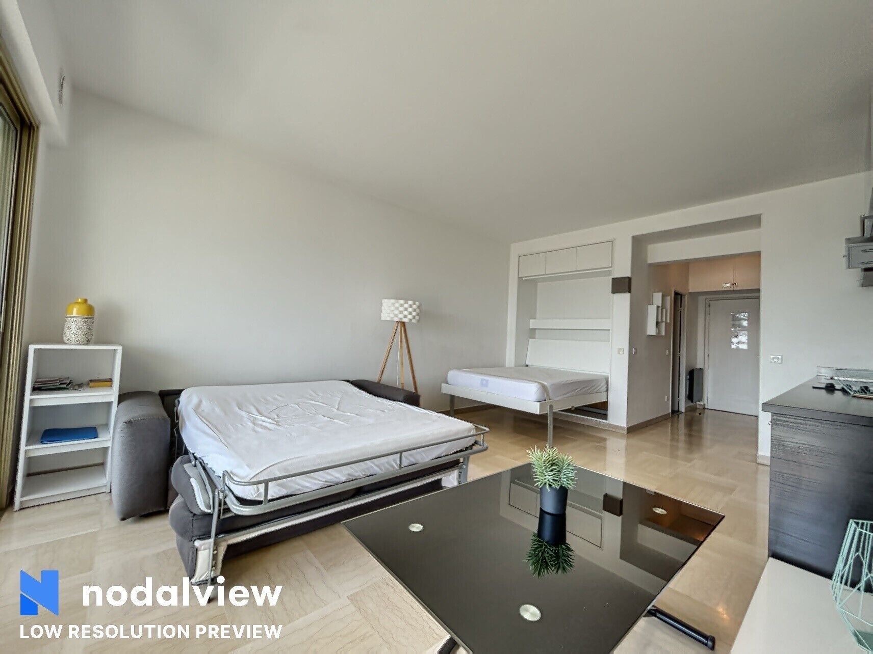 A modern bedroom with a bed, bedside table, lamp, and a small shelf with a decorative item.