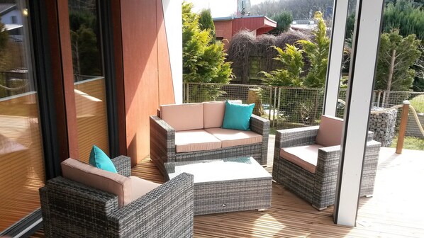 A covered outdoor seating area with wicker furniture and cushions.
