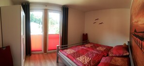 A bedroom with a bed, a sliding glass door leading to a balcony, and a wall with bird silhouettes.