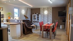 Una sala de estar moderna con comedor, cocina y televisor.