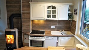 Una cocina compacta con alacenas blancas, estufa, horno y lavavajillas.
