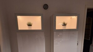 Zwei weiße Kühlschränke mit beleuchteten Oberflächen und einer Uhr an der Wand.