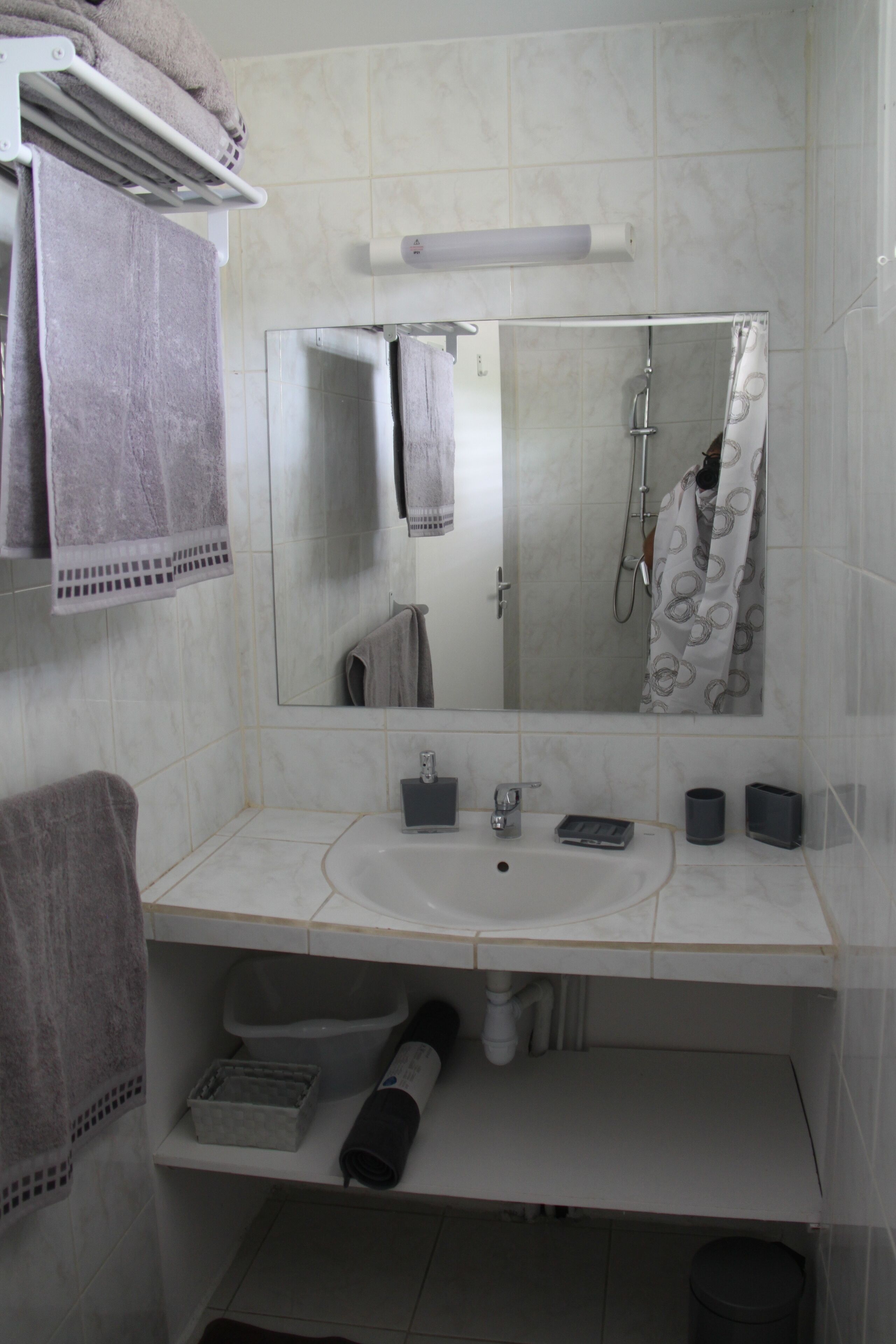 A bathroom with a white sink, mirror, and towel rack.