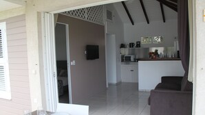 A dining area with a table set for two, a kitchen in the background, and a living area with a couch.