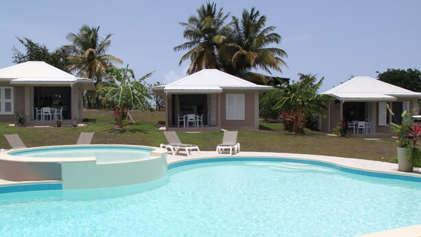 A swimming pool with lounge chairs and a covered seating area.