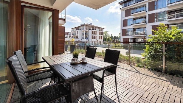 A balcony with a table and chairs, a view of a building, and a parking sign.