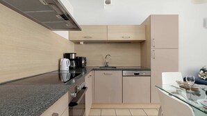 A modern kitchen with a granite countertop, stainless steel appliances, and a glass dining table.