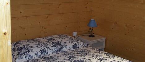 Ein Zimmer mit einem Bett, einem Nachttisch und zwei an der Wand befestigten Bildern.
