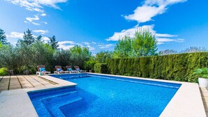 A rectangular swimming pool with a tiled edge, surrounded by lounge chairs and a hedge. - Country house Can Flauta with pool in Mallorca (Selva)