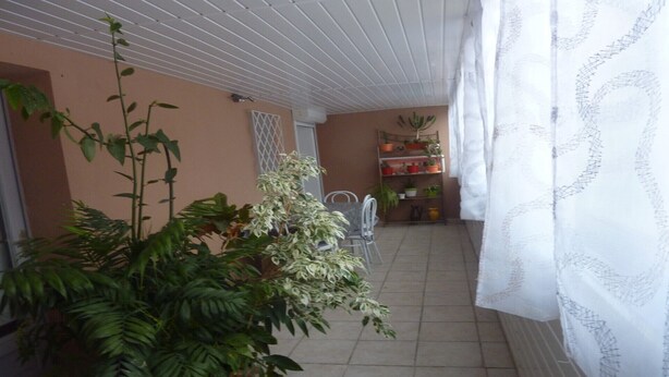 Ein Balkon mit Topfpflanzen, einem Stuhl und einem Fliesenboden.