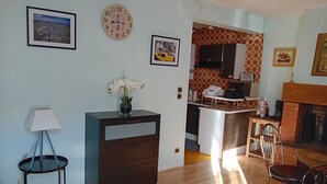 A living room with a wooden floor, a dark-colored cabinet, a lamp, a clock, and a framed picture on the wall.