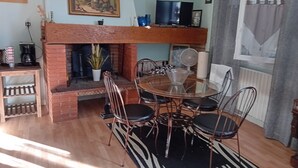 A dining area with a brick fireplace, a round glass table, and metal chairs.