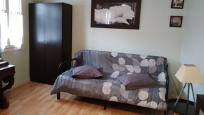 A room with a sofa, a cabinet, and a lamp.