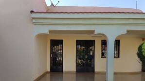 A building with a beige exterior, a red roof, and a tiled entrance area.
