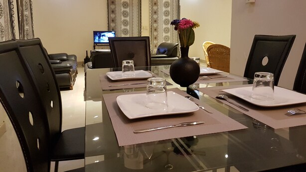 A dining area with a glass table, black chairs, and a vase with flowers.