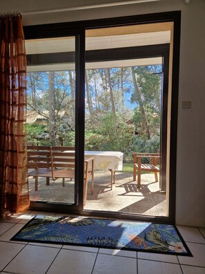 A room with a sliding glass door leading to an outdoor area with a table and benches. - House with shared pool 30m far, 100 m from the Golf de l'Ardilouse (Lacanau Océan)