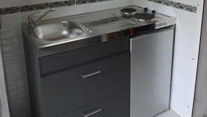 A compact kitchen with a sink, stove, and two drawers.