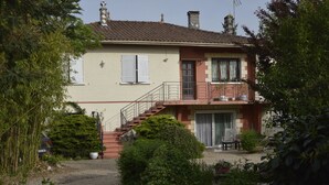 A two-story house with a balcony, a staircase, and a garden area.