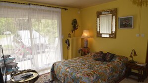 A bedroom with a bed, a lamp, a mirror, and a window with curtains.