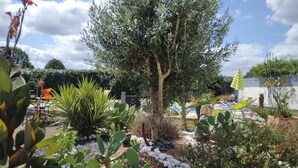 A garden with a variety of plants, a tree, and a pool area with lounge chairs. - SMALL RELAXATION CORNER (Seyresse)