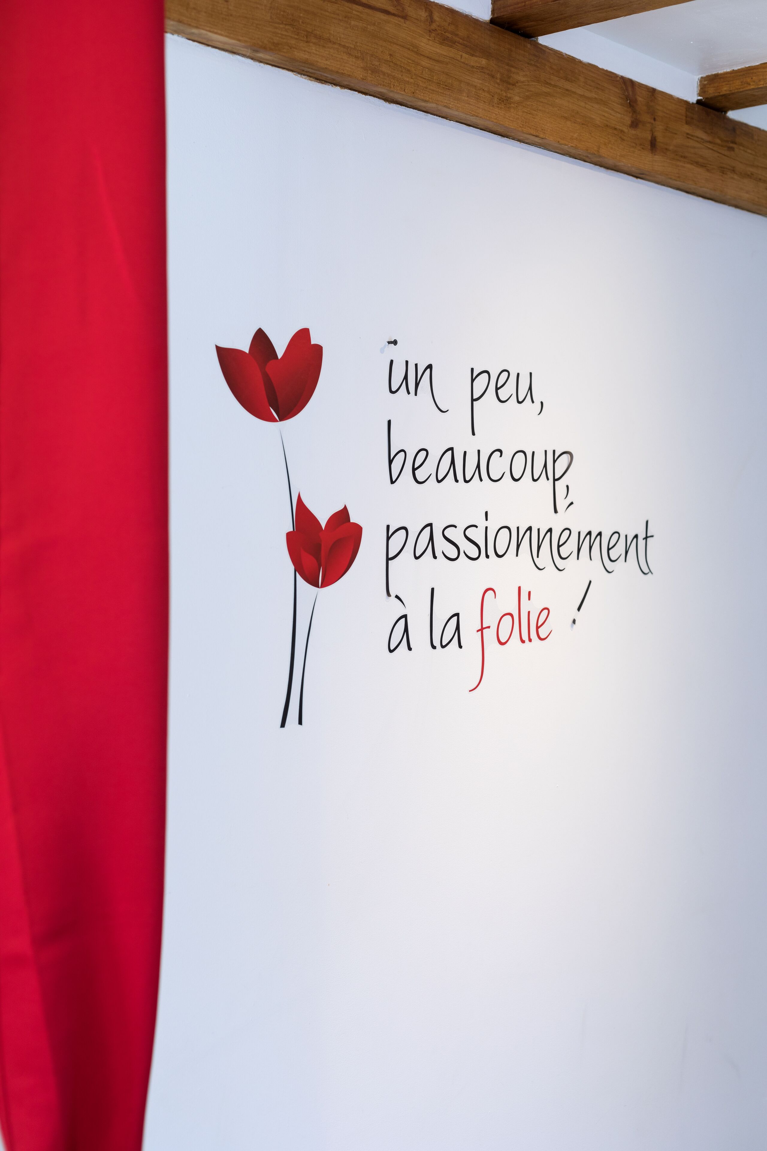 Un mur orné d’une phrase en français et de deux illustrations de fleurs rouges.