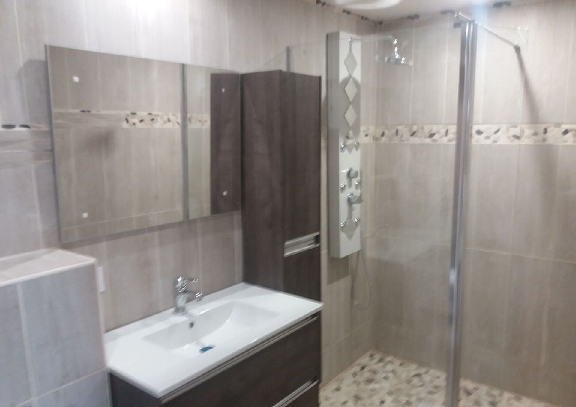 A modern bathroom with a large mirror, a sink, and a shower area.
