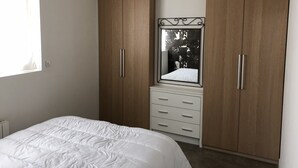 Camera da letto con un letto, un'armadio in legno e uno specchio.