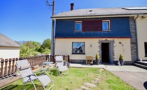A two-story house with a balcony, a wooden fence, and outdoor seating.