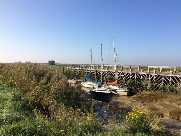 A dock with boats and a wooden pier extending into a body of water, surrounded by vegetation. - Les Prés de la Rivière, Maintenay (Maintenay)
